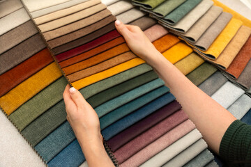 Hands holding fabric swatches for custom furniture and upholstery, textile samples for interior design, home decoration and creative material selection.