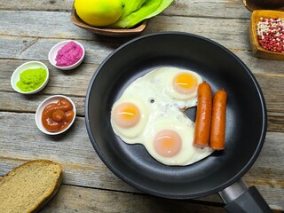 delicious appetizing breakfast of fried eggs and sausages on a frying pan