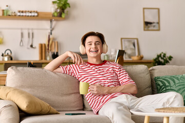 Fototapeta premium Young man enjoys online studies in a cozy modern apartment while sipping coffee