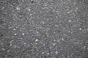 Texture, background of dark asphalt with small stones and cracks