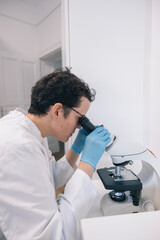 Female doctor analyzing samples using a microscope in a medical laboratory