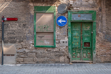 Old Weathered Stone Wall With Green Wooden Door. Urban decay facade, vintage architecture, traditional Mediterranean building, aged masonry