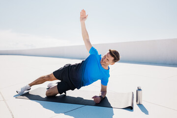 Man doing side plank exercise on rooftop with water bottle nearby