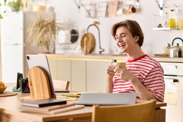 Young man enjoys studying online while sipping tea in his cozy modern apartment