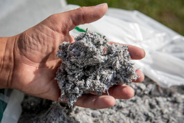 Hand holding cellulose insulation material made from recycled paper.  Eco friendly construction, sustainable housing, energy efficiency and green building solutions