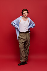 Fototapeta premium Stylish young man showcases trendy outfit against vibrant red backdrop