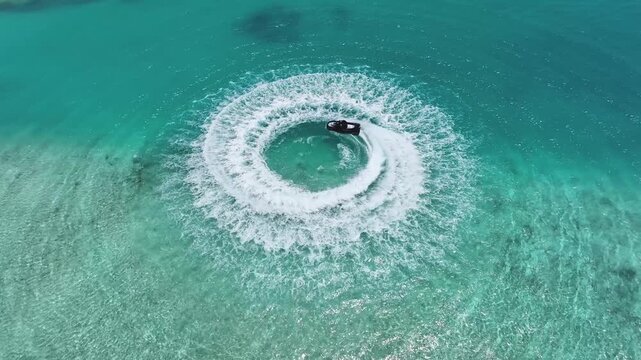 Aerial view of a jet ski leaving a circular white wake in the turquoise waters near Gulhi, SouthMaleAtoll, Maldives.