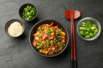 Delicious fried rice in bowl served on grey textured table, flat lay