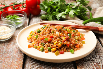Delicious fried rice with vegetables and bacon served on wooden table, closeup