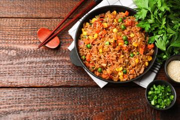 Delicious fried rice in baking dish served on wooden table, flat lay. Space for text