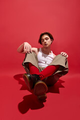 Stylish young man showcases trendy outfit on vibrant red backdrop
