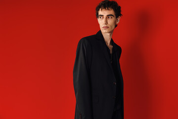 Obraz premium Handsome man showcasing elegant style against vibrant red backdrop in a modern fashion setting