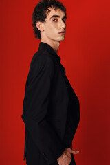 Obraz premium Handsome stylish man in elegant attire poses confidently against a vibrant red background