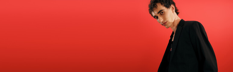 Handsome stylish man showcasing modern elegance against a vibrant red background