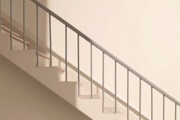 A staircase with a railing and a shadow on the wall. The railing is made of metal and the steps are white