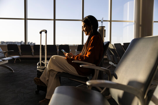 Businesswoman using smartphone while waiting in airport terminal