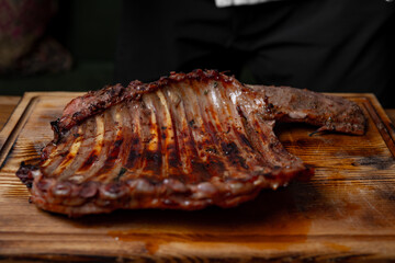 Grilled pork ribs with barbecue seasoning served on a rustic wooden board, juicy roasted meat with smoky flavor and charred edges in a closeup food photography