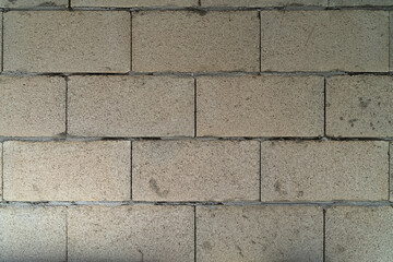 Gray concrete block wall features visible texture and imperfections, highlighting construction materials, suitable for backgrounds or architectural design projects with copy space for text