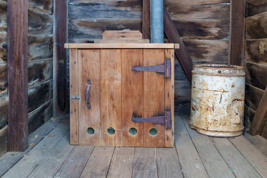 Wooden box toilet inside an old timber outhouse. Sawdust can beside the toilet. Queensland, Australia 