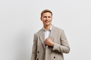 Smiling man dressed in stylish gray blazer and white shirt looks confidently at camera on plain white background, studio portrait. People lifestyle concept.