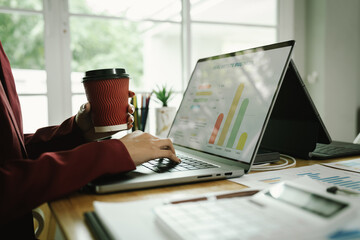 Businessperson analyzing financial charts with laptop and documents, symbolizing data analysis, investment planning, and business growth strategy.