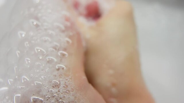 Close-up macro view of hands covered in soapy lather, gently washing under water with delicate iridescent bubbles, highlighting hygiene, cleanliness, and skin care routines