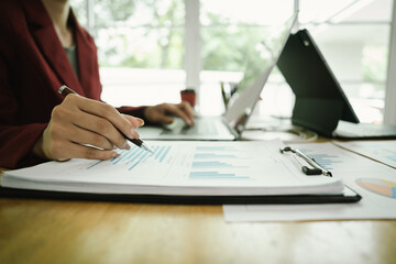 Obraz premium Businessperson analyzing financial charts with laptop and documents, symbolizing data analysis, investment planning, and business growth strategy.