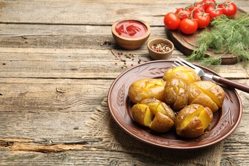 Tasty baked potatoes, fork and products on wooden table. Space for text