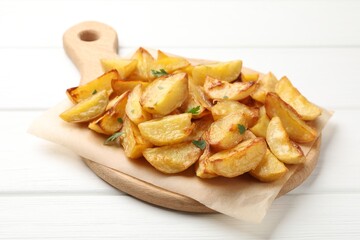 Tasty baked potatoes with parsley on white wooden table, closeup
