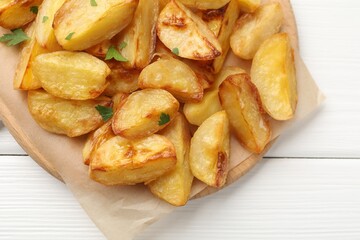 Tasty baked potatoes with parsley on white wooden table, top view
