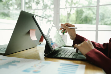 Businessperson analyzing financial charts with laptop and documents, symbolizing data analysis, investment planning, and business growth strategy.