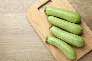 Fresh ripe zucchinis on wooden table, top view. Space for text