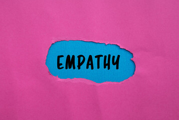 Empathy message written on ripped torn pink paper on blue background. Conceptual Empathy symbol....