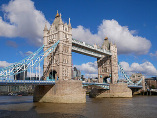 Obraz premium Tower Bridge spanning the River Thames in London on a sunny day with blue sky and clouds