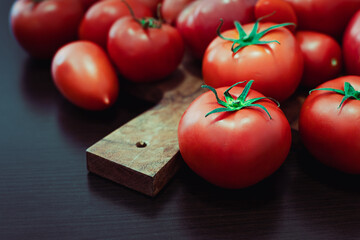 Fresh ripe red tomatoes placed on a rustic wooden cutting board, concept of organic farming,...