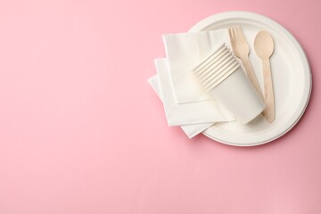 Set of disposable tableware on pink background, top view. Space for text