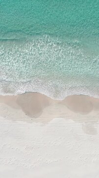 Vertical aerial view of foamy waves and turquoise water on white sand beach, Kangaroo Island, South Australia