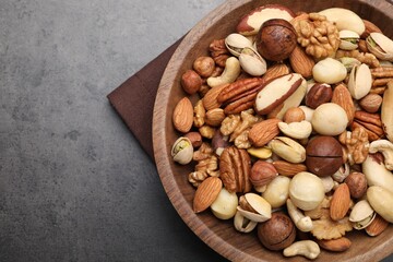 Mix of different nuts in bowl on grey table, top view. Space for text