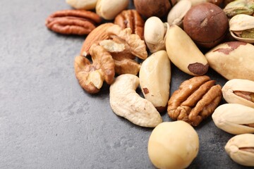 Mix of different nuts on grey table, closeup. Space for text