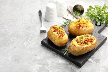 Tasty stuffed baked potatoes served on grey textured table, space for text