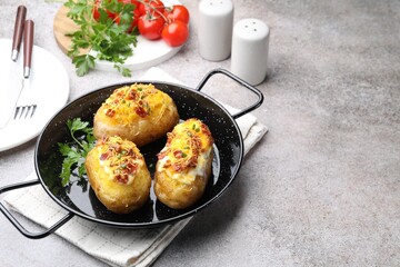 Tasty stuffed baked potatoes in baking dish served on grey table, space for text