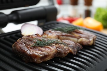 Electric grill with tasty meat onion and dill indoors, closeup