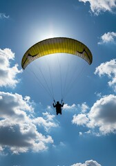 Paraglider flying against blue sky with clouds