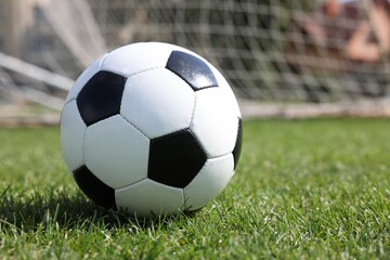 Soccer ball on green grass outdoors, space for text. Football game