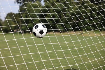 Hitting soccer ball in net outdoors, closeup. Football game