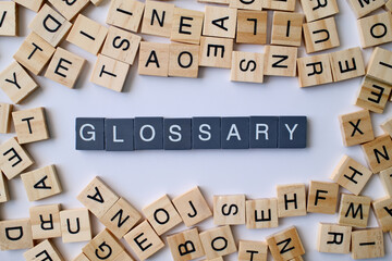 Glossary word in wooden cube blocks, alphabetical dictionary concept, collection of terms and definitions, education and reference idea