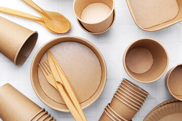 Set of disposable tableware on white tiled table, flat lay