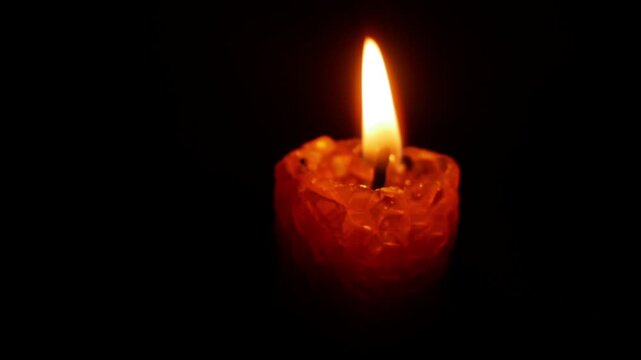 Red candle with flickering flames set against a dark backdrop, providing a serene ambiance perfect for relaxation, meditation, or creating a cozy environment for gatherings