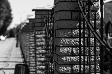 A detailed shot of a brick and wrought iron fence, with a shallow depth of field, creating a sense of linear perspective.

