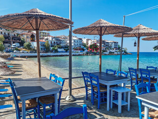 Blue Restaurant tables from a traditional Greek taverna overlooking the Mediterrenean sea with turqoise blue waters in the background, Skala Marion, Thassos island, Northern Greece
